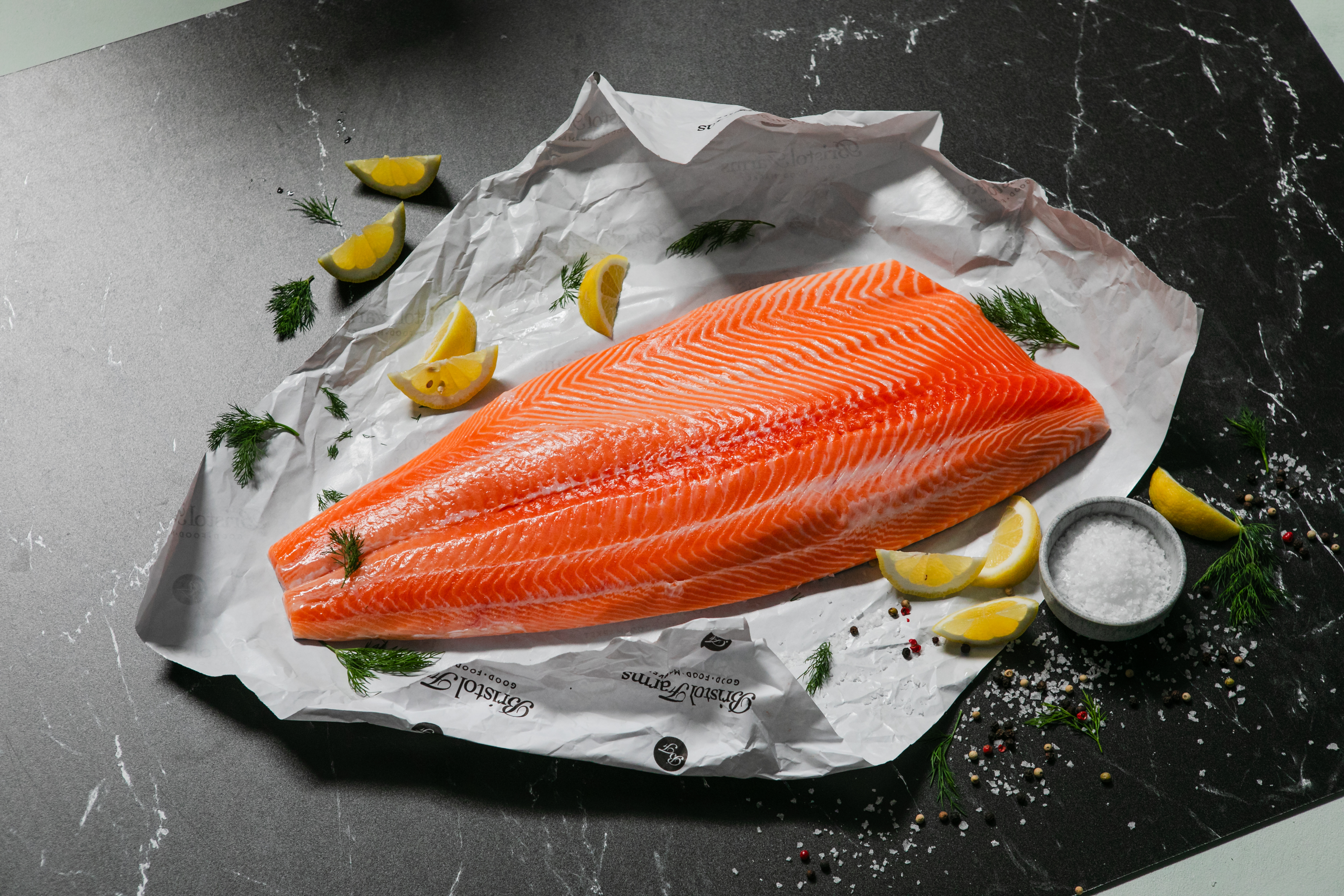 salmon fillet on a black marble counter with lemons